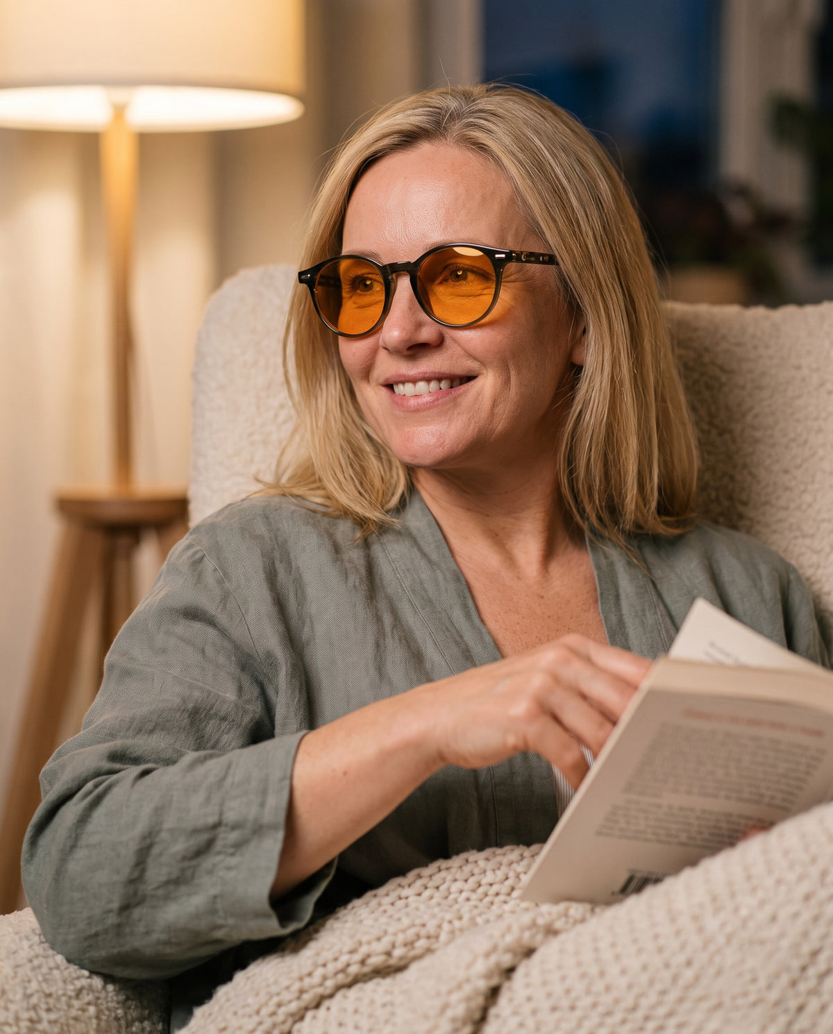 Woman reading in an armchair wearing Seluna amber glasses